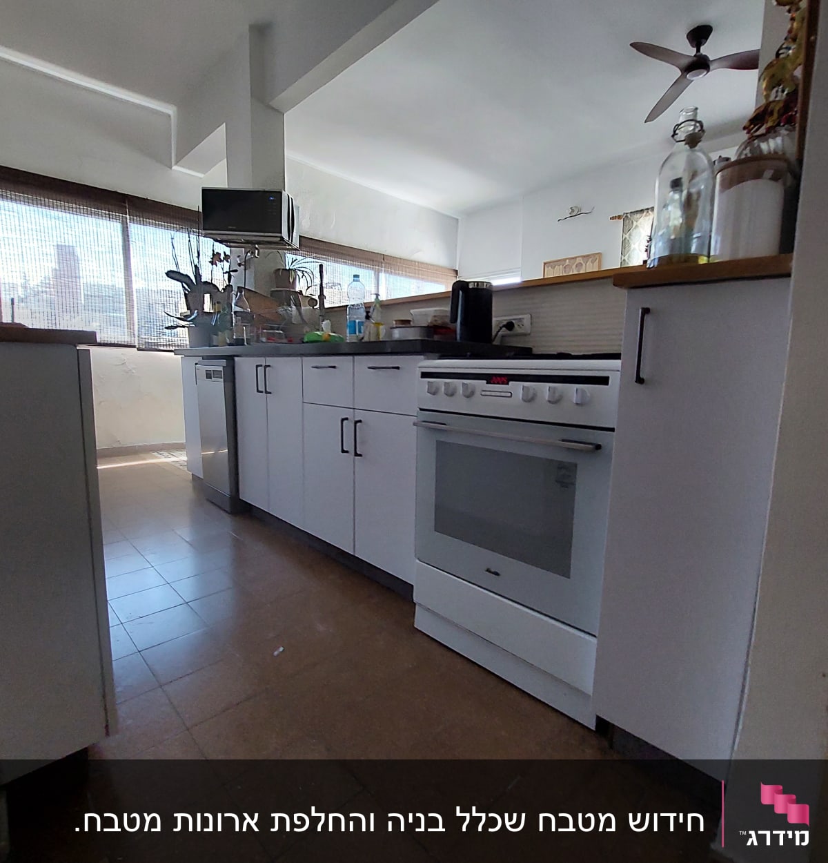 מטבח עם תנור לבן, ארונות וכלים על השיש